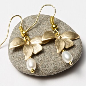 May include: Gold butterfly earrings with a single white pearl dangling from each earring.