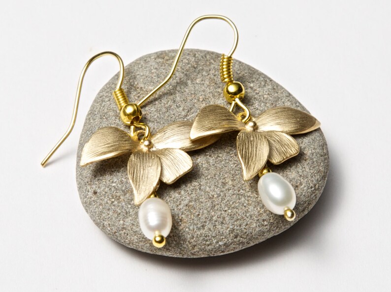 May include: Gold butterfly earrings with a single white pearl dangling from each earring.