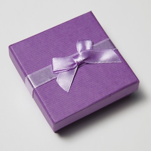 May include: A small, purple gift box with a lavender satin ribbon tied in a bow.