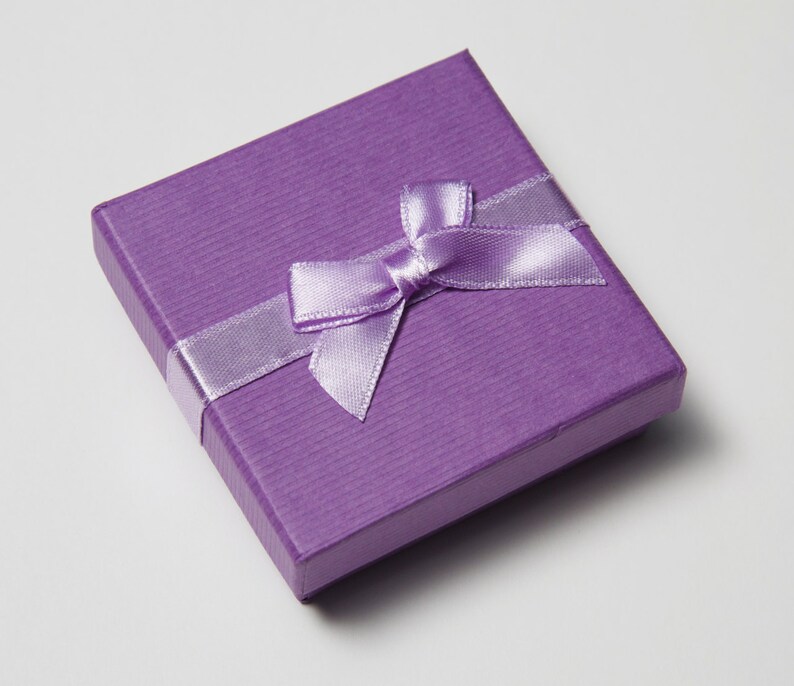 May include: A small, purple gift box with a lavender satin ribbon tied in a bow.