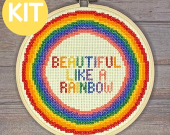 May include: A cross-stitch embroidery kit featuring a rainbow with the text "Beautiful Like A Rainbow". The kit is displayed in a wooden embroidery hoop.
