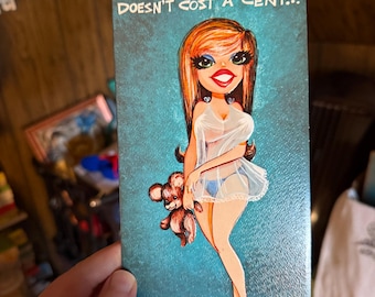 May include: Vintage birthday card with a cartoon illustration of a woman holding a teddy bear. The card has a teal background and the text "FOR YOUR BIRTHDAY I'M GOING TO GIVE YOU SOMETHING THAT DOESN'T COST A CENT..."