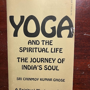 May include: A tan-colored book with the title "Yoga and the Spiritual Life: The Journey of India's Soul" by Sri Chinmoy Kumar Ghose. The book cover features a large black "Yoga" title and a smaller black text block describing the book's contents.