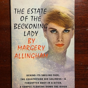 May include: Vintage paperback book cover for "The Estate of the Beckoning Lady" by Margery Allingham. The cover features a woman with blonde hair and blue eyes. The title and author's name are prominently displayed in bold text. The cover also includes text about the book's plot.