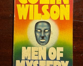 May include: A vintage book cover with a yellow, orange, red, green, and blue background. The title is "Men of Mystery" with the subtitle "A Celebration of the Occult". The cover features a blue face mask with white eyes.