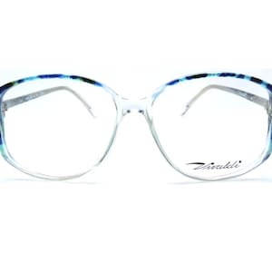 May include: Clear blue and green tortoiseshell eyeglasses with a silver frame and the word "Vivakli" printed on the right lens.