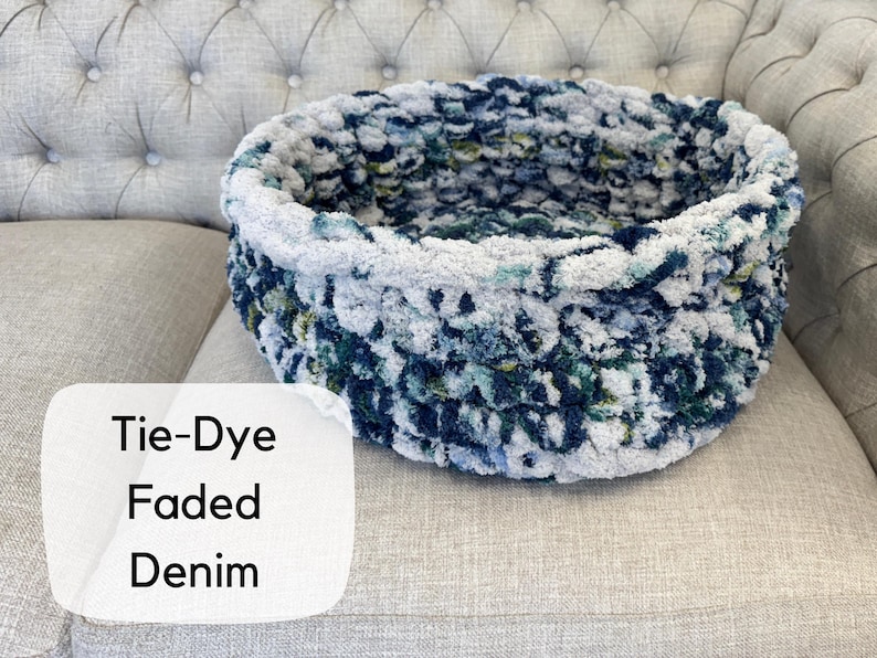 Puede incluir: Una cesta redonda te&ntilde;ida con efecto tie-dye en color denim descolorido. La cesta est&aacute; hecha de un material suave y afelpado en tonos azules, blancos y verdes. El texto "Tie-Dye Faded Denim" est&aacute; en una etiqueta blanca.
