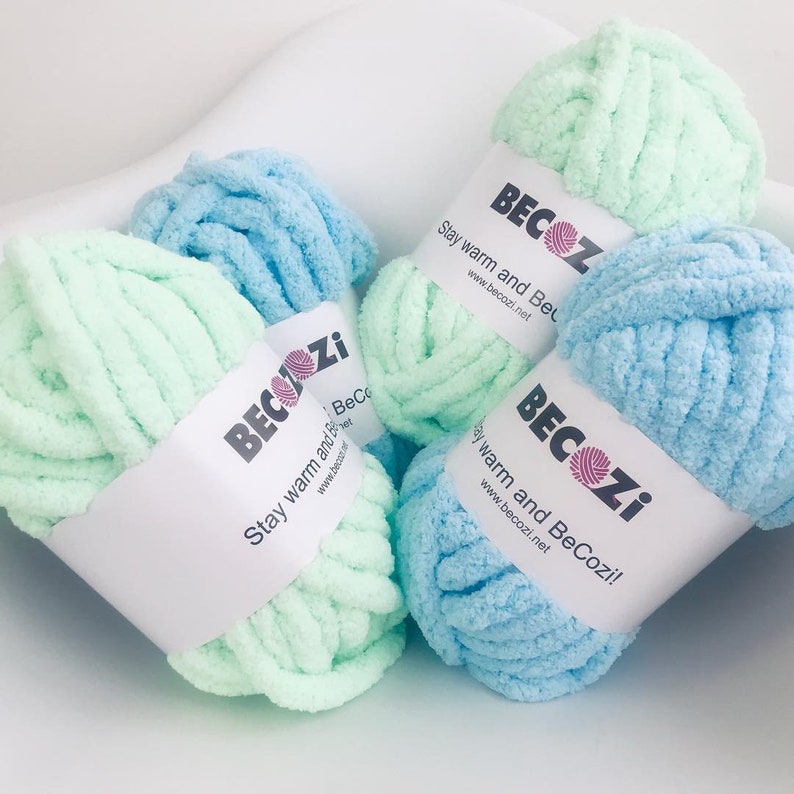 May include: Two skeins of yarn, one light green and one light blue, with the brand name "BeCozi" and the slogan "Stay warm and BeCozi!" printed on the labels.