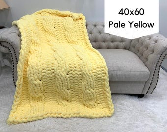 May include: A pale yellow chunky knit throw blanket featuring a prominent cable knit pattern. The blanket measures 40x60 inches as indicated by the text overlay. The thick yarn creates a textured, looped appearance across the entire surface.