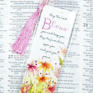 May include: Clear bookmark with a pink tassel. The bookmark features the words "May the Lord Bless you and keep you" with floral illustrations in orange, yellow, and red.