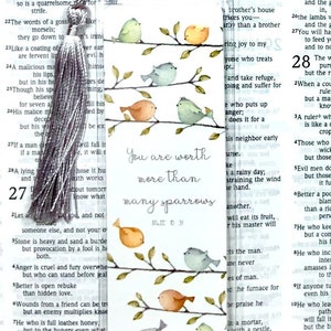 May include: A watercolor bookmark with a white background and a branch with five colorful birds. The text "You are worth more than many sparrows" is written in black ink. The reference "Matt 10:31" is written in smaller font below the text.