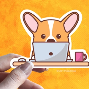 May include: A cartoon sticker of a corgi dog working on a laptop computer at a desk with a pink coffee mug. The sticker has a white border and the text "&copy; 2021 Pixels&Paws" at the bottom.