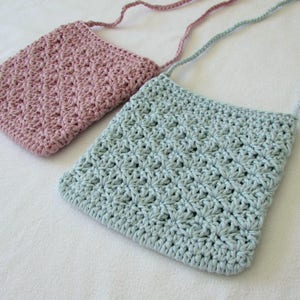May include: Two crocheted bags with adjustable straps. One bag is light blue and the other is pink.