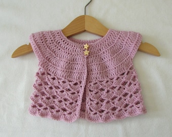 Op de afbeelding: Een roze gebreid babyvest met een gegolfde rand en stervormige knopen.