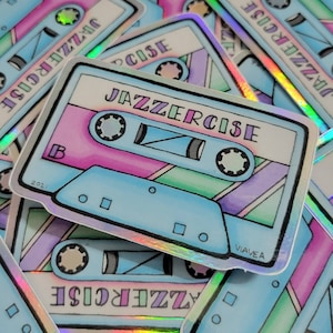 May include: A blue and pink cassette tape sticker with the text "Jazzercise" and the year "2021" printed on it. The sticker has a holographic finish.