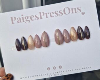 May include: Set of ten press-on nails with a nude, brown, and gold color scheme. The nails have a subtle gold line design.  The nails are displayed on a white background with the text "PaigesPressOns."