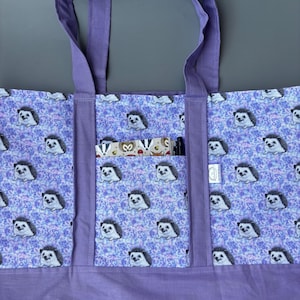 K&ouml;nnte beinhalten: Lilafarbene Einkaufstasche mit Rei&szlig;verschlussfach und Igel-Druck. Die Tasche hat zwei Henkel und ein kleines Fach auf der Vorderseite.