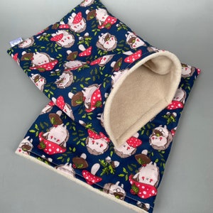 May include: A blue and white fabric pouch with a white fleece lining. The pouch is decorated with a repeating pattern of hedgehogs and mushrooms.