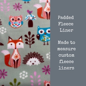 May include: A green fabric with a woodland animal print featuring owls, foxes, hedgehogs, and birds. The text "Padded Fleece Liner Made to measure custom fleece liners" is on the right side of the image.