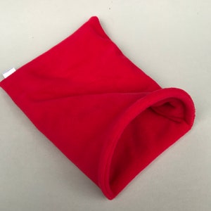 May include: A red fleece pet bed shaped like a burrow. The bed has a small opening for the pet to enter.