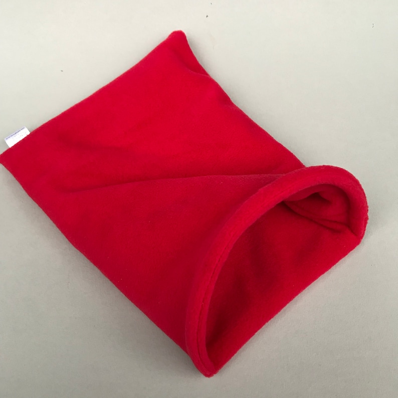 May include: A red fleece pet bed shaped like a burrow. The bed has a small opening for the pet to enter.