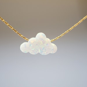 May include: A delicate gold chain necklace with a white opal cloud pendant.
