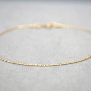 Könnte beinhalten: Eine zarte goldene Kettenkette mit einem schlichten Design.