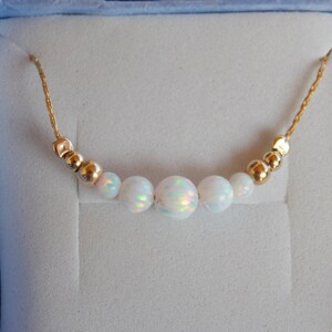 May include: A delicate gold chain necklace with five white opal beads and gold spacer beads.