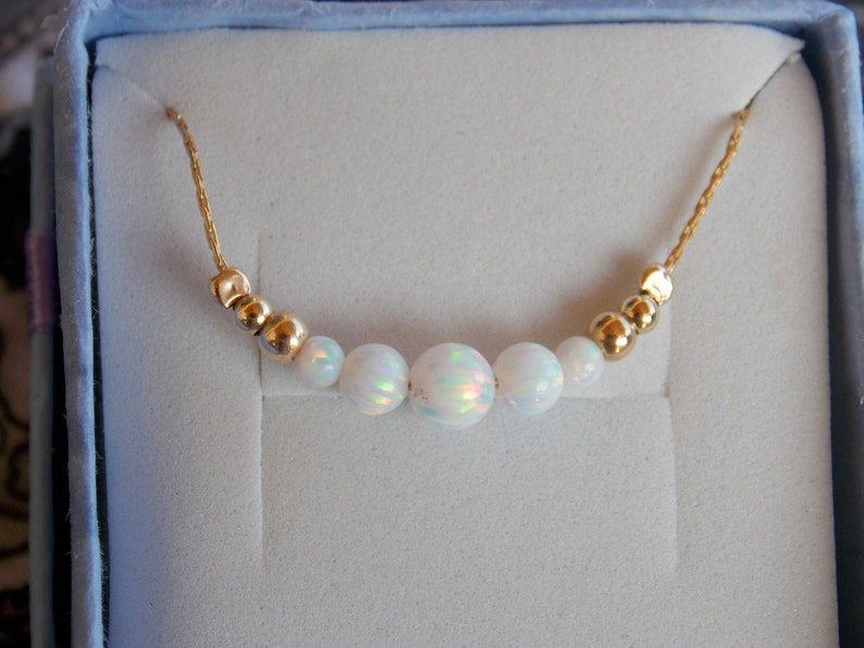 May include: A delicate gold chain necklace with five white opal beads and gold spacer beads.