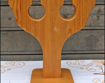 May include: A wooden candle holder with three arms, each with a circular opening. The holder is made of natural wood with a light brown finish. It has a square base.