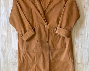 May include: A long brown suede coat with a double breasted closure and two large pockets. The coat has a collar and long sleeves.