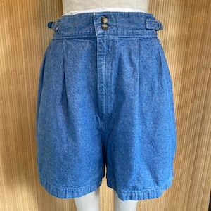 Op de afbeelding: Hoge taille denim shorts met plooien en een knoopsluiting. De shorts zijn lichtblauw van kleur en hebben een ontspannen pasvorm.