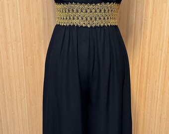 May include: A black sleeveless maxi dress with a gold embroidered belt. The dress has a V-neckline and a flowing skirt.