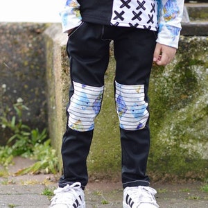 May include: Black pants with a white and blue patterned fabric on the knees.