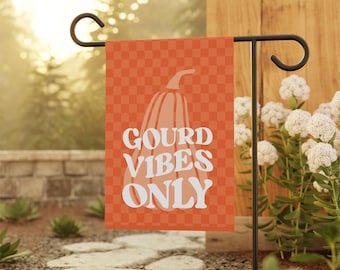 Peut inclure: Un drapeau de jardin rectangulaire avec un motif à carreaux orange et orange clair. Une grande illustration de citrouille de couleur claire est centrée sur le drapeau, avec le texte blanc GOURD VIBES ONLY en police ondulée et rétro.