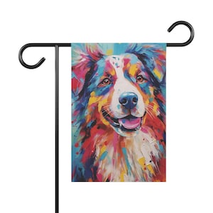 May include: A rectangular garden flag featuring a vibrant, multi-colored abstract painting of a dog with a white blaze on its face, blue nose, and open mouth. The artwork uses bold brushstrokes of red, yellow, blue, and pink, suspended on a black metal stand.