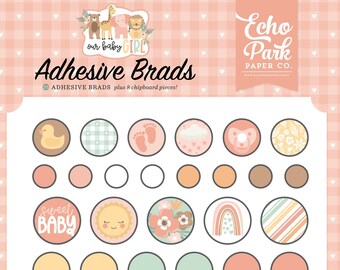 May include: A collection of baby-themed adhesive brads and chipboard pieces. The set includes circular designs with images of a duck, footprints, a pacifier, and a rainbow. Other pieces include a teddy bear, baby shoes, and banners with text like "Sweet Baby" and "Stay Wild".