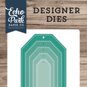 May include: A set of five teal-colored die-cut tags with stitched edges. The tags are nested within each other, with the largest tag at the top and the smallest tag at the bottom. The tags are designed to be used for crafting and scrapbooking.
