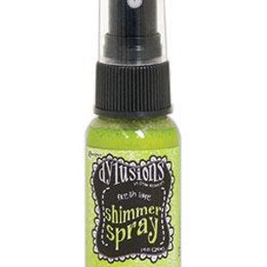 May include: A small green bottle of DYLUSIONS Shimmer Spray. The bottle has a black spray nozzle and a white label with black text.
