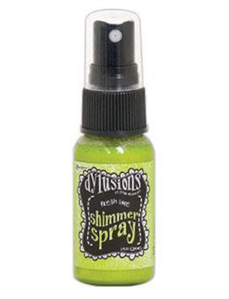 May include: A small green bottle of DYLUSIONS Shimmer Spray. The bottle has a black spray nozzle and a white label with black text.