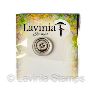 May include: A clear button with a silver-colored center and four holes is displayed on a white card. The card has the text "Lavinia Stamps" and a mushroom illustration. The background has a colorful, abstract design.