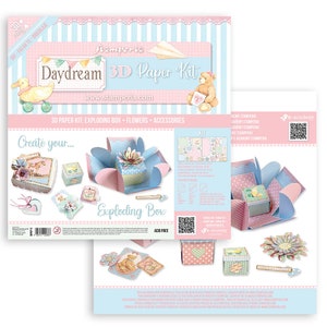 May include: A 3D paper craft kit called "Daydream" by Stamperia. The kit includes an exploding box, flowers, and accessories. The box is pink and blue with a floral design. The kit is acid-free.