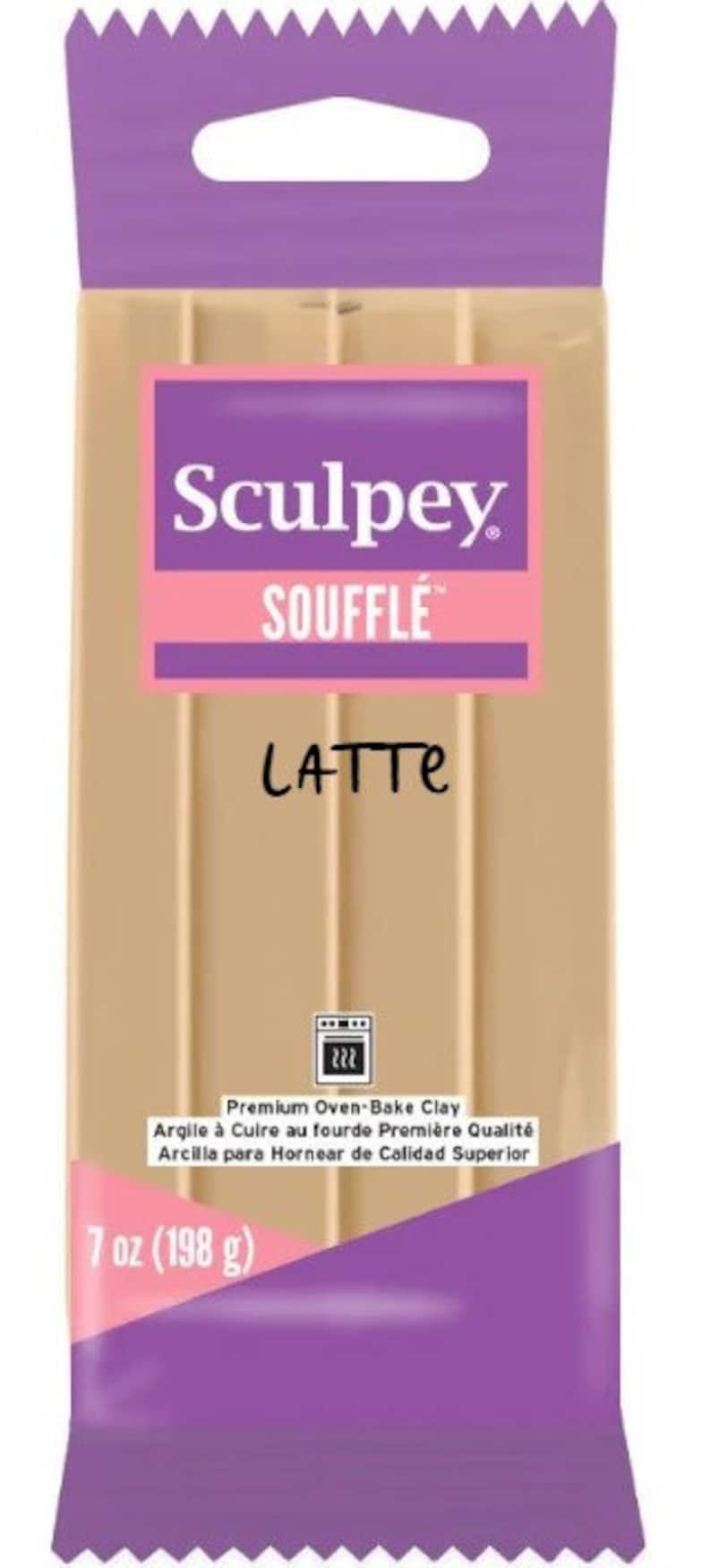 Pu&ograve; includere: Un pacchetto di pasta modellabile Sculpey Souffle Latte da cuocere in forno. La confezione &egrave; viola con un foro di sospensione bianco. La pasta &egrave; di colore marrone chiaro. La confezione riporta la scritta "Argilla per Forno di Qualit&agrave; Superiore" e "7 oz (198 g)".