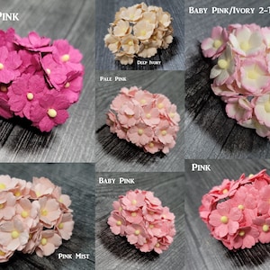 May include: Assortment of paper flower clusters in various shades of pink, including deep pink, pale pink, baby pink, and pink mist. The flowers have yellow centers and are arranged in a cluster.