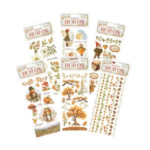 May include: A collection of decorative rub-on transfers featuring whimsical autumn and fairy tale themes. Designs include fairies, gnomes, mushrooms, fall foliage, and inspirational phrases. The transfers are in shades of orange, green, and brown.