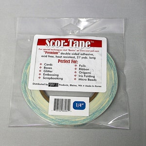 May include: A roll of Scor-Tape "Premium" double-sided adhesive tape in a clear plastic bag. The tape is 1/4 inch wide and is labeled as acid free, heat resistant, and 27 yards long. The tape is perfect for cards, boxes, glitter, embossing, scrapbooking, foils, ribbon, origami, iris folding, and micro beads.