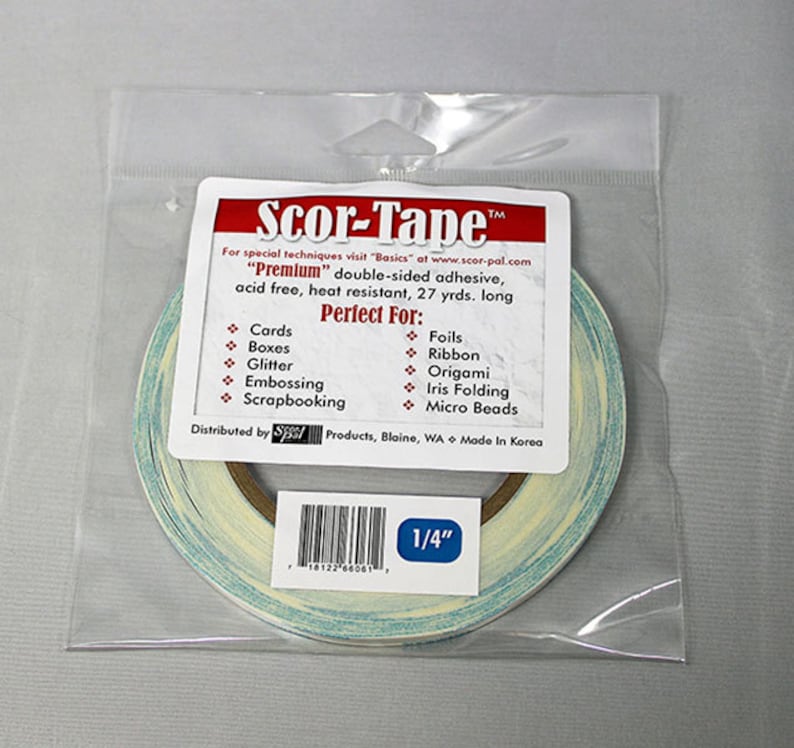 May include: A roll of Scor-Tape "Premium" double-sided adhesive tape in a clear plastic bag. The tape is 1/4 inch wide and is labeled as acid free, heat resistant, and 27 yards long. The tape is perfect for cards, boxes, glitter, embossing, scrapbooking, foils, ribbon, origami, iris folding, and micro beads.