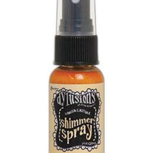 May include: A small bottle of gold shimmer spray with a black spray nozzle and a white label that says "Dylushions Shimmer Spray".