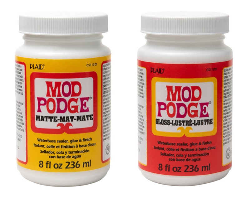 May include: Two white plastic bottles of Mod Podge, one with a yellow label and the other with a red label. The yellow label reads "MATTE-MAT-MATE" and the red label reads "GLOSS-LUSTR&Eacute;-LUSTRE". Each bottle contains 8 fl oz (236 ml) of waterbase sealer, glue, and finish.