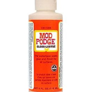 May include: A 4-ounce bottle of Mod Podge Gloss-Lustre, a water-based sealant, glue, and finish for all surfaces. The bottle is white with a light beige liquid inside. The label is orange with white text and a green logo.